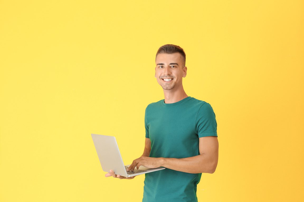 Young Man with Laptop on Color Background